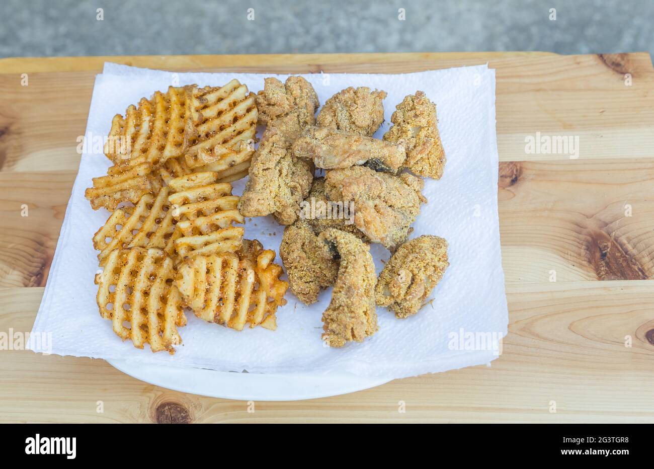 Piatto di nugget di pesce di merlano appena cucinati e fritte di waffle messi su un asciugamano di carta. Foto Stock