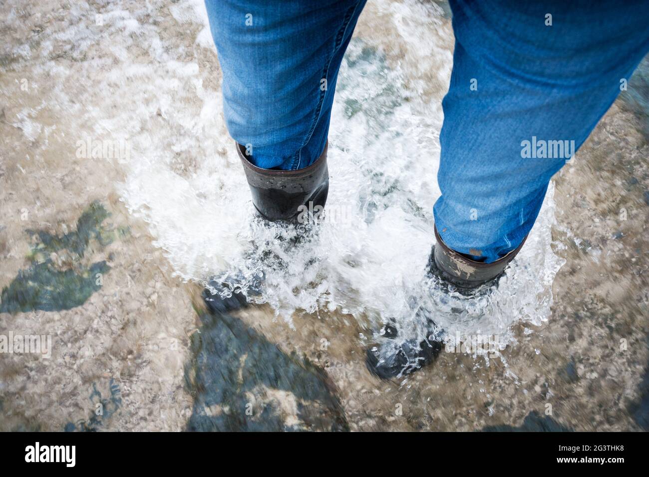 In piedi in acqua galleggiante con stivali di gomma Foto Stock