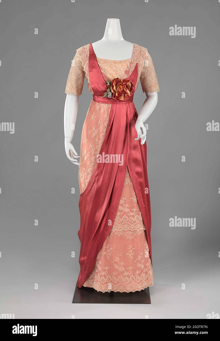 Vestitevi con gonna per hobble. La lunga silhouette diritta introdotta dal fashion designer parigino Paul Poiret nel 1906 raggiunse il suo apice nel 1909 con la gonna hobble. Era così stretto che le donne potevano camminare solo con piccoli passi di rimescolamento. Questo abito è composto da tre strati tenuti insieme da una cintura di raso. Il grande cordino di fiori è tipico della moda fino alla prima guerra mondiale. Foto Stock