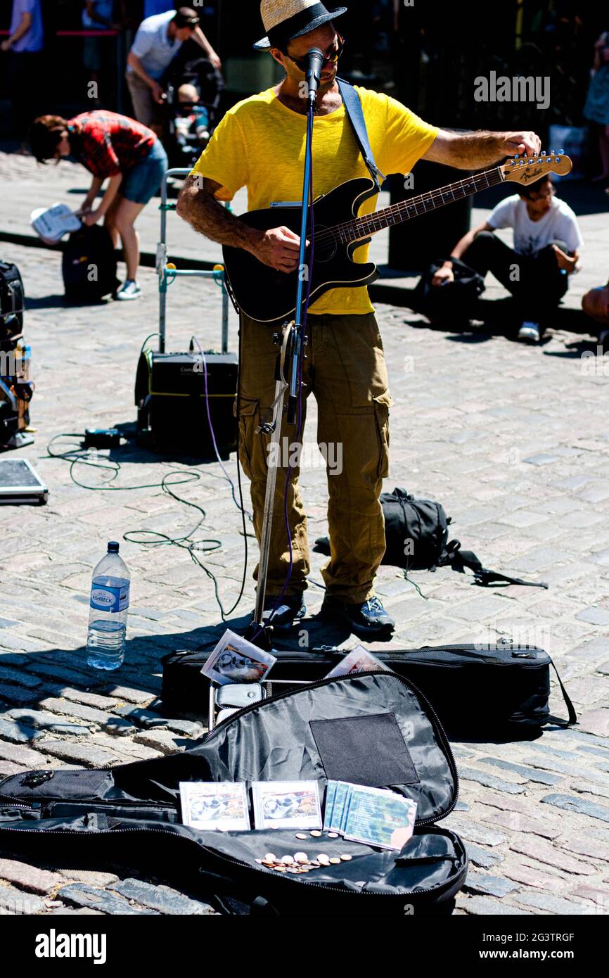Un busker maschile che sintonizza una chitarra elettrica, Londra, Inghilterra, Regno Unito. Foto Stock