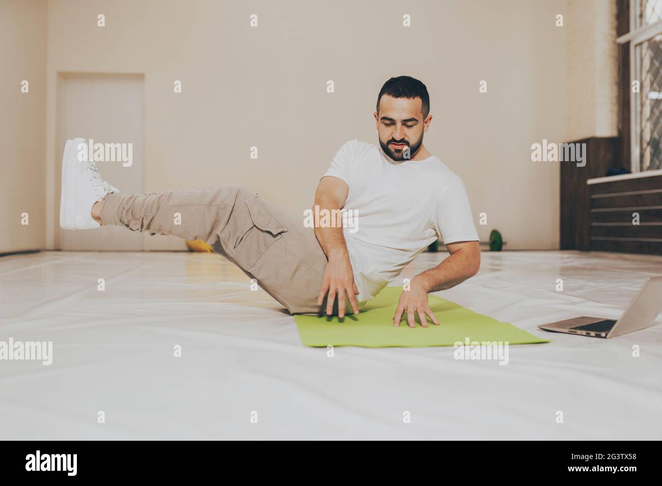 Angolo basso. Giovane bell'uomo che fa scricchiolette e cerca video di lavoro online sull'uso del laptop. Guerriero giovane auto motivato Foto Stock