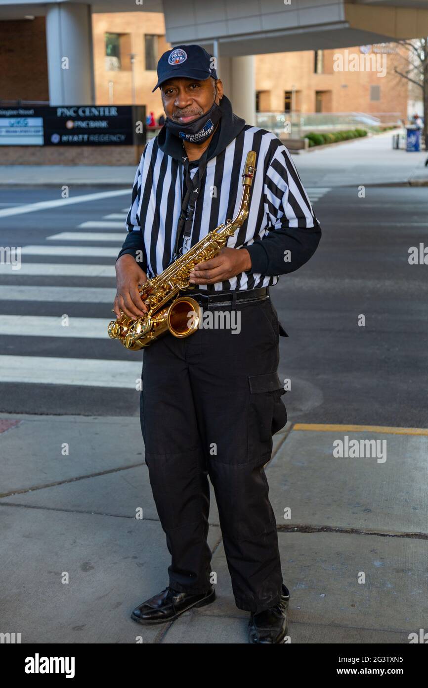 Un amichevole musicista di strada veste come arbitro mentre si gioca il sassofono per i tifosi che partecipano al torneo di finale quattro NCAA nel centro di Indianapolis. Foto Stock
