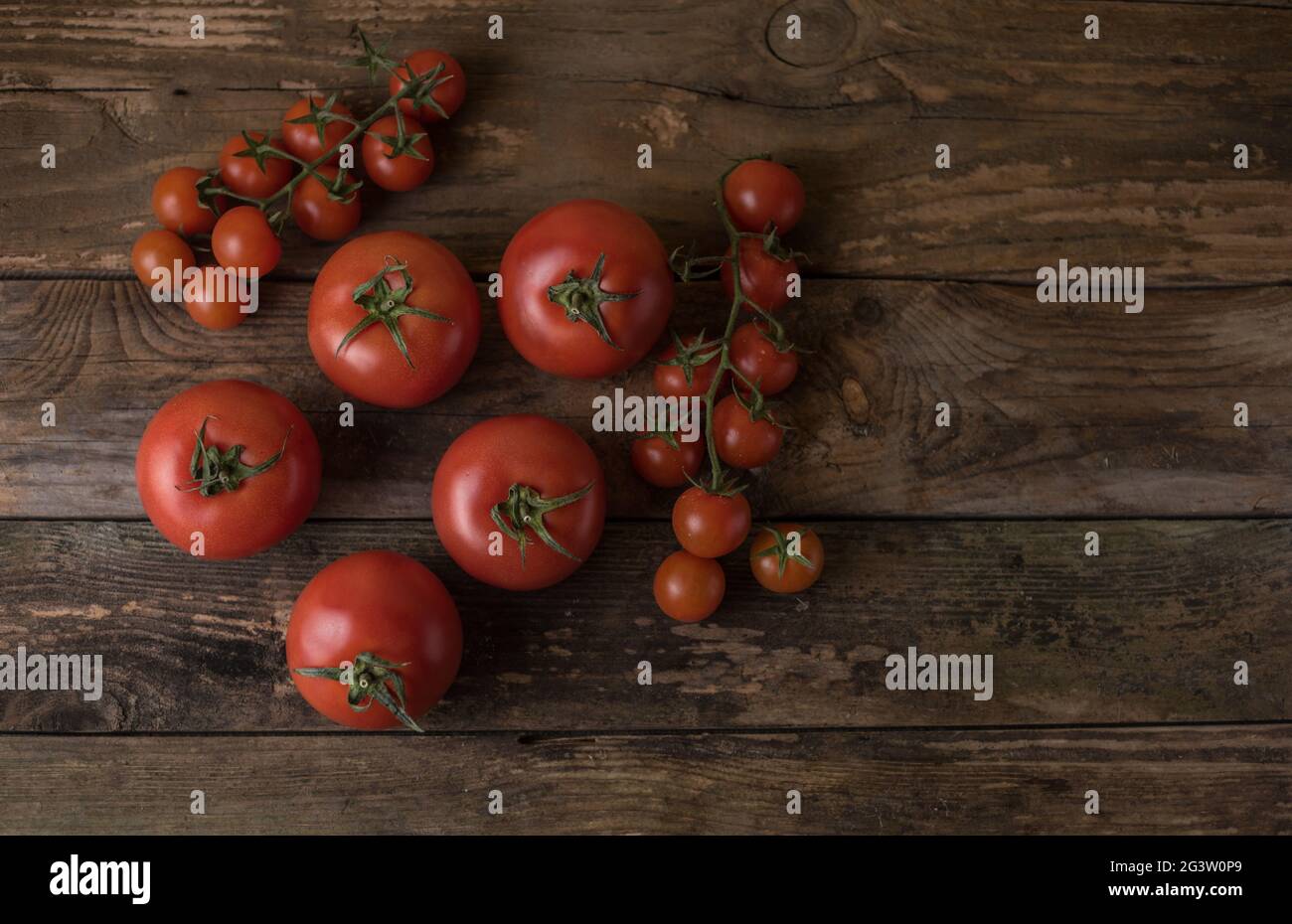 Pomodori freschi e maturi su vecchi pomodori in legno e piccoli pomodori Foto Stock
