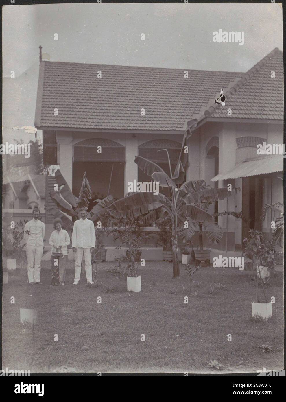 Due uomini e una donna davanti a una casa nelle Indie Orientali olandesi. Parte del libro degli studenti della scuola coloniale per ragazze e donne dell'Aia parte II (1930-1949). Foto Stock