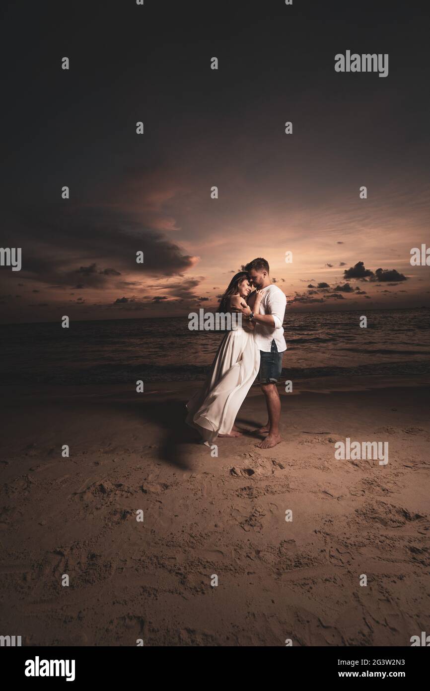 Coppia romantica sulla spiaggia durante il tramonto Foto Stock
