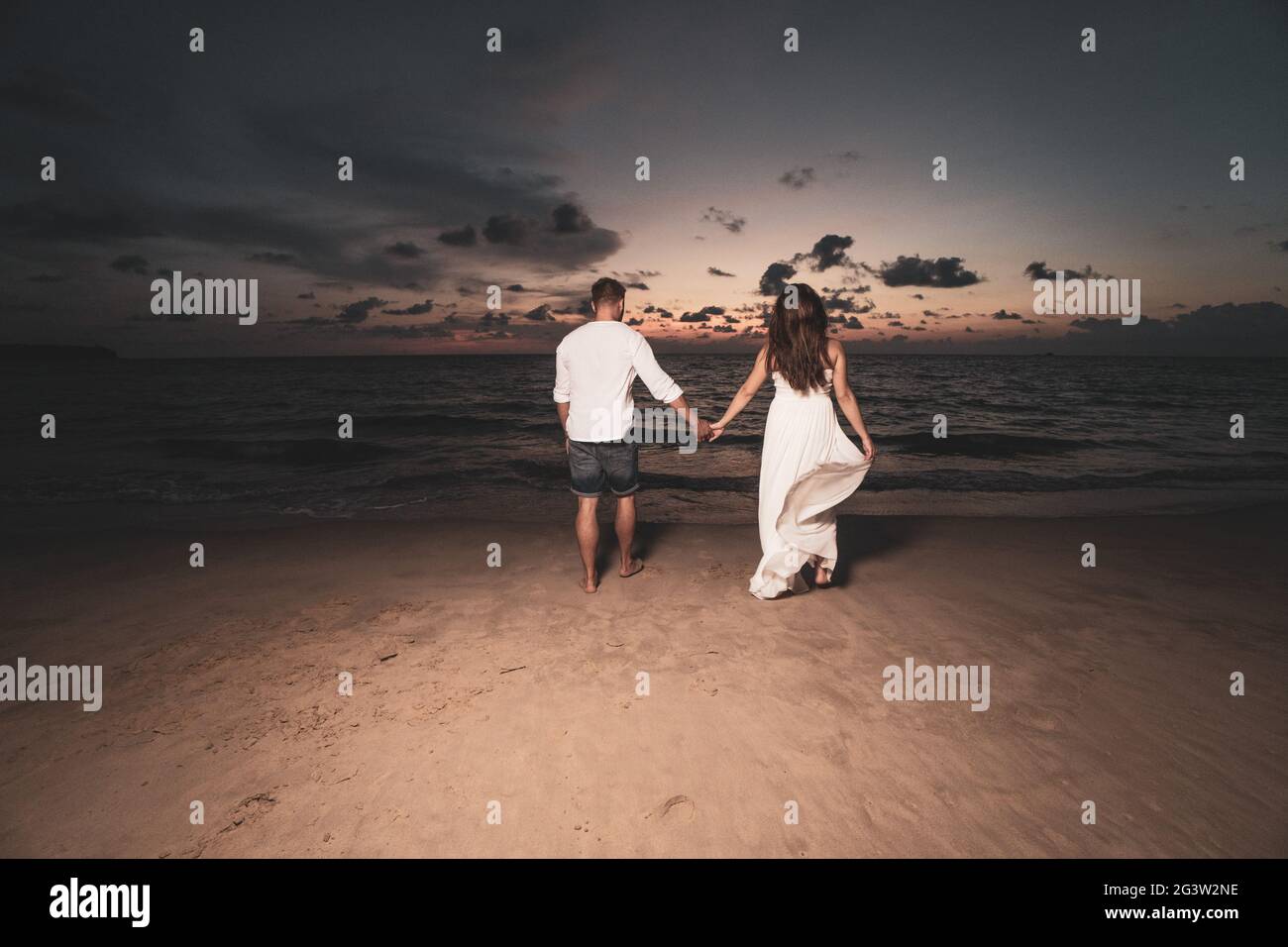 Coppia romantica sulla spiaggia durante il tramonto Foto Stock