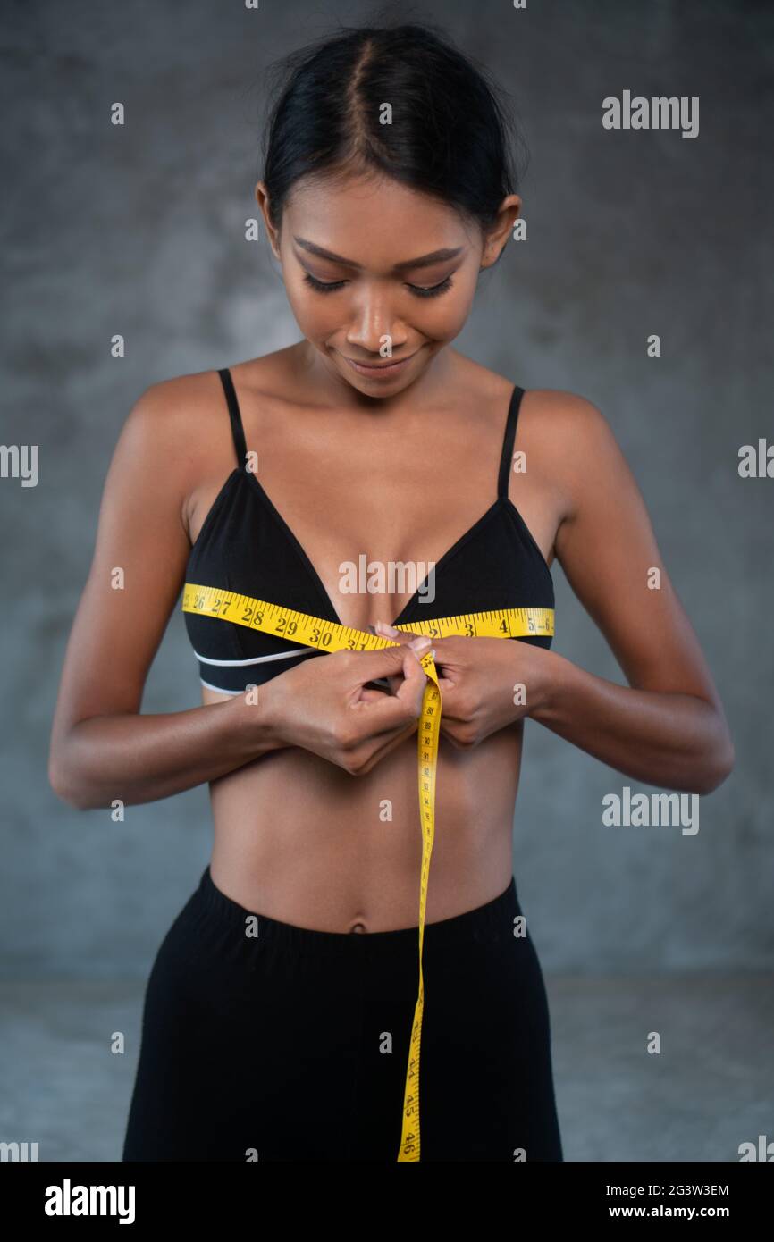 Donna sorridente sana con metro a nastro in palestra Foto Stock