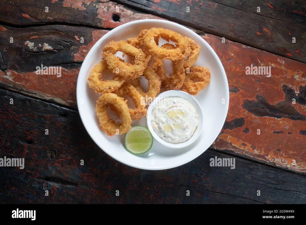 Anelli di calamari fritti con salsa di immersione isolata su rustico tavolo di legno Foto Stock