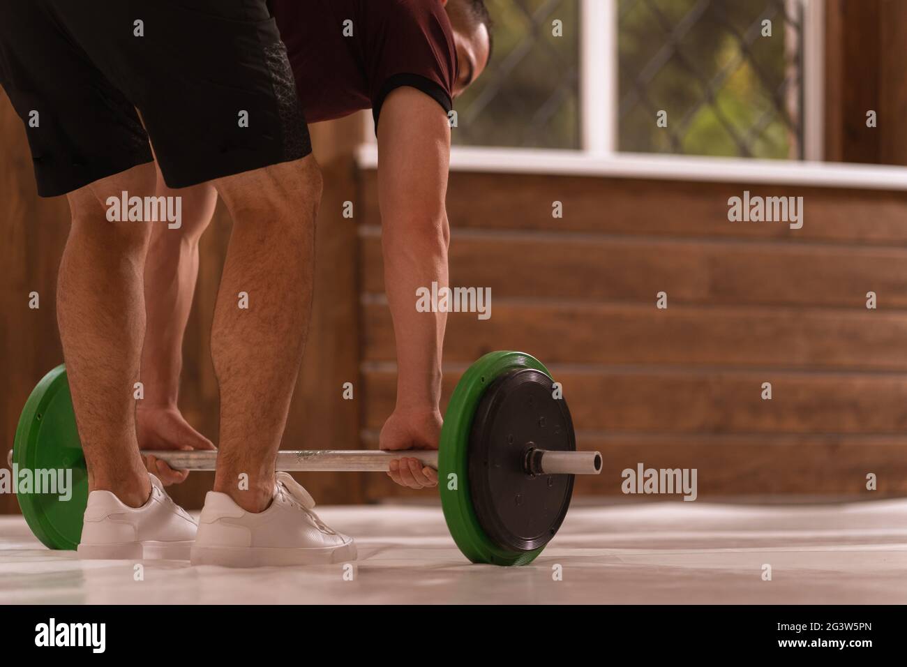 Giovane uomo sportivo piegato afferrare un set di pesi attrezzature per l'allenamento del peso a casa. Attrezzature sportive per la formazione. Tra. Funzionale Foto Stock