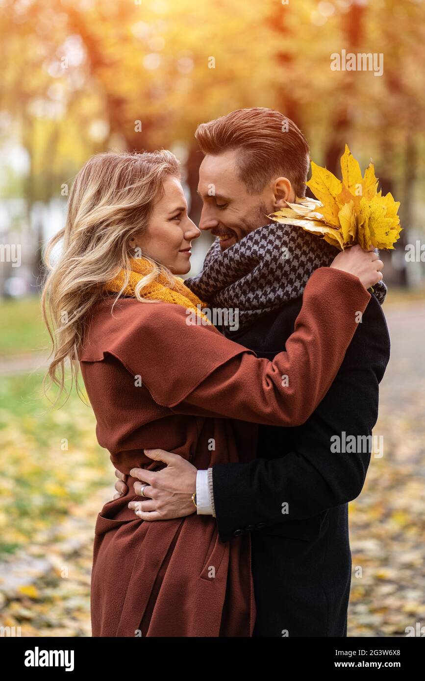 Ritratto di mezza lunghezza di una giovane coppia baciante. Marito e una moglie hanno abbracciato il sorriso guardarsi l'un l'altro nel parco autunnale. Outdoo Foto Stock