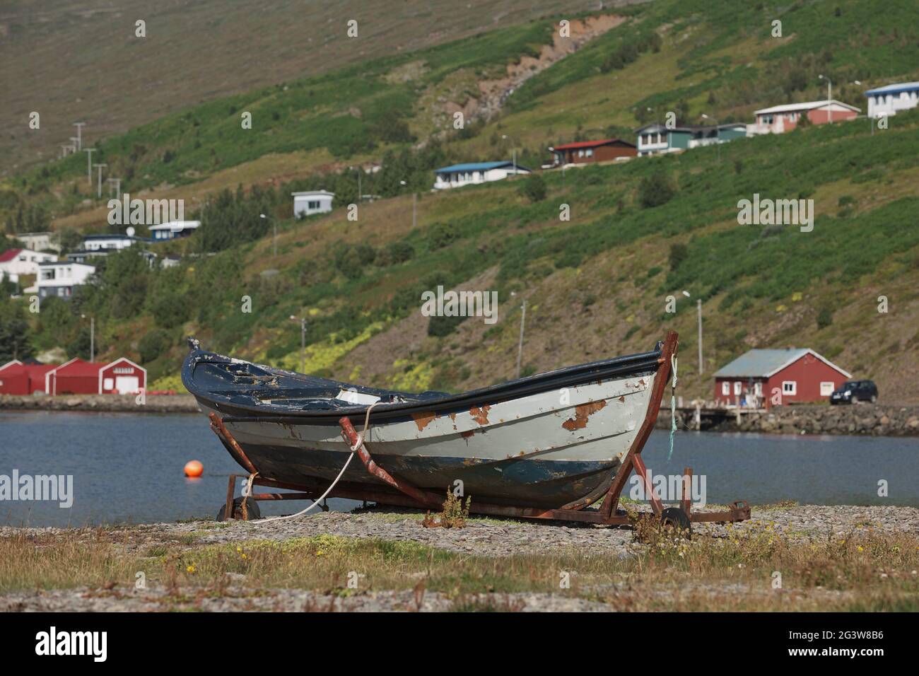 Vecchia barca d'epoca con una piccola città di Eskifjordur situato nell'Islanda orientale sullo sfondo Foto Stock