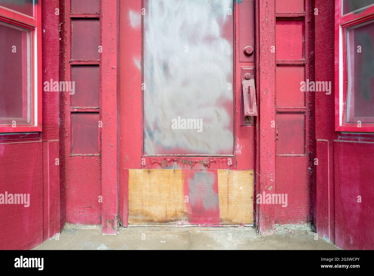 La parte inferiore di una porta distrutta ad un edificio rosso Foto Stock