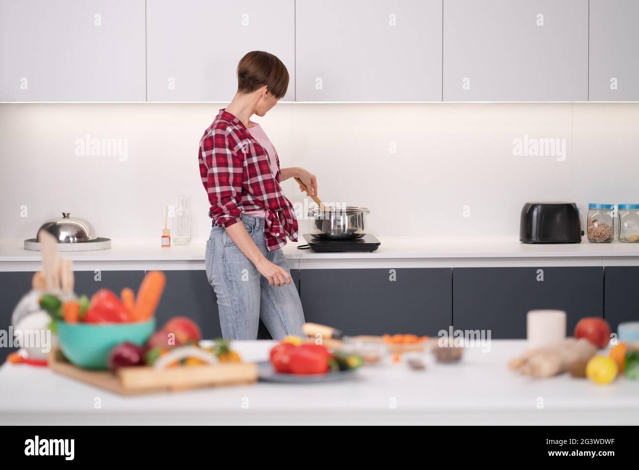 Bella donna cucina cena per grande famiglia piatto mescolando nel piatto in piedi lateralmente alla macchina fotografica. Cibo sano vivere. Salute Foto Stock