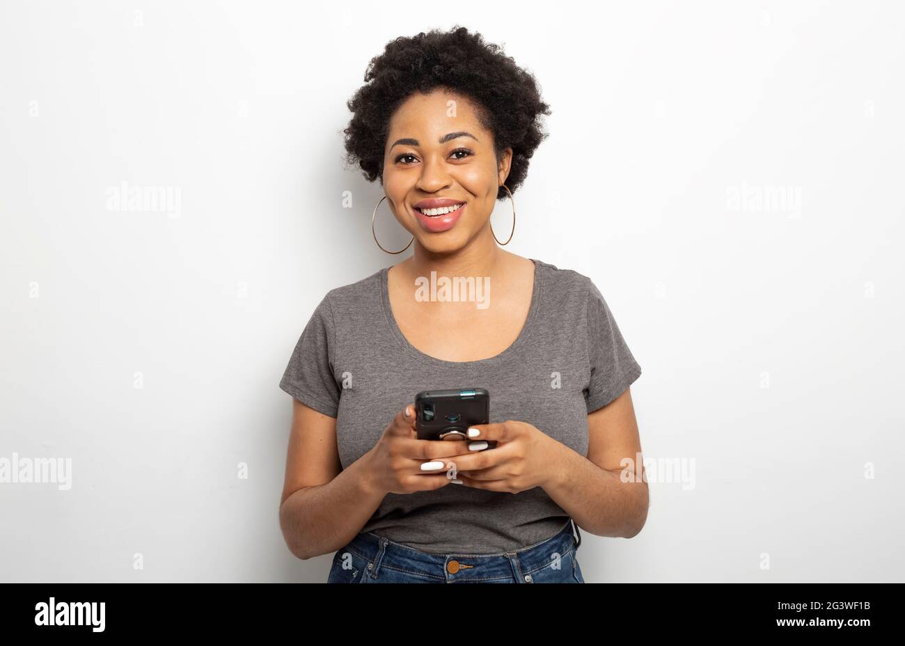 Ritratto di una donna africana sorridente che tiene un telefono. Foto Stock Ritratto di una donna africana sorridente che tiene un telefono. Foto Stock