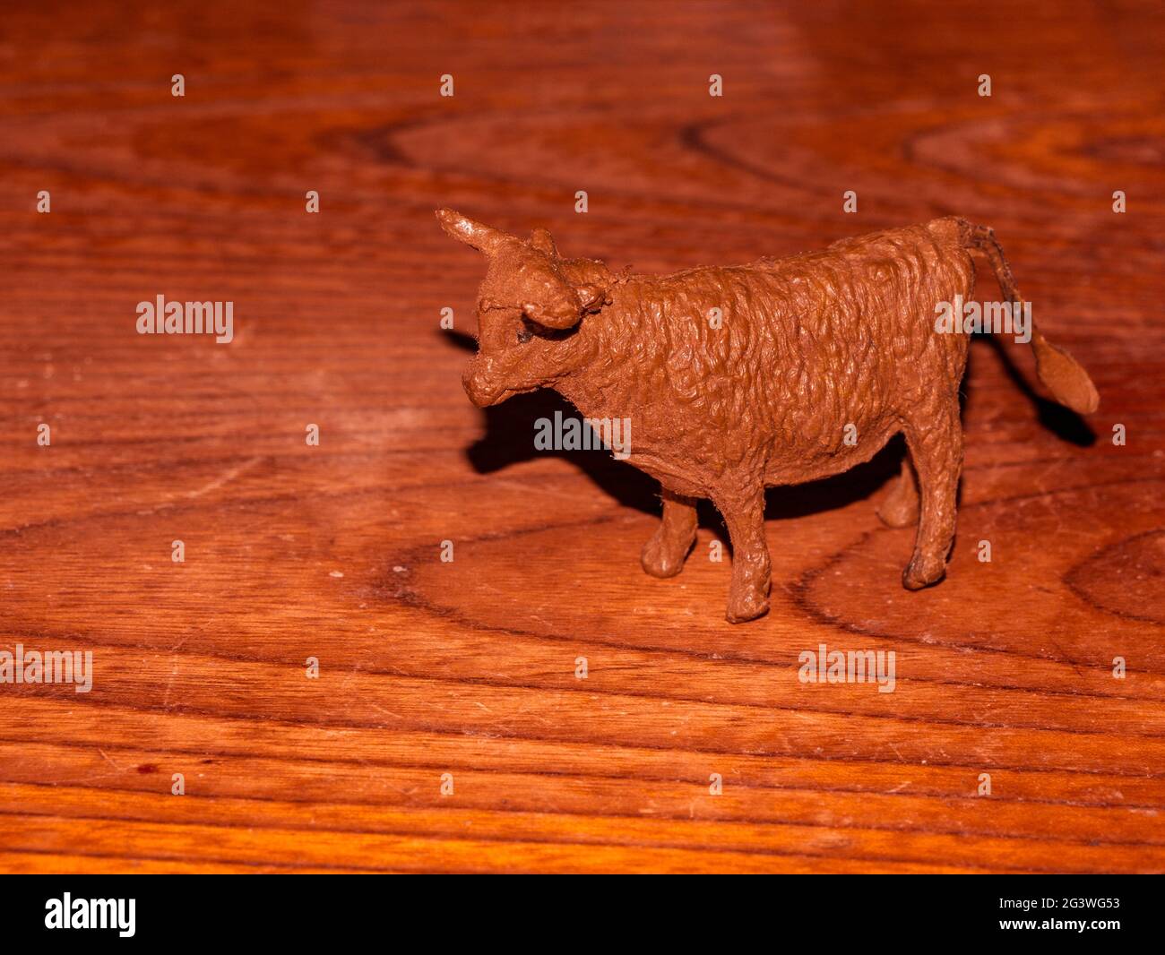 Vecchia statuina di mucca marrone polverosa con corna, su sfondo di legno Foto Stock