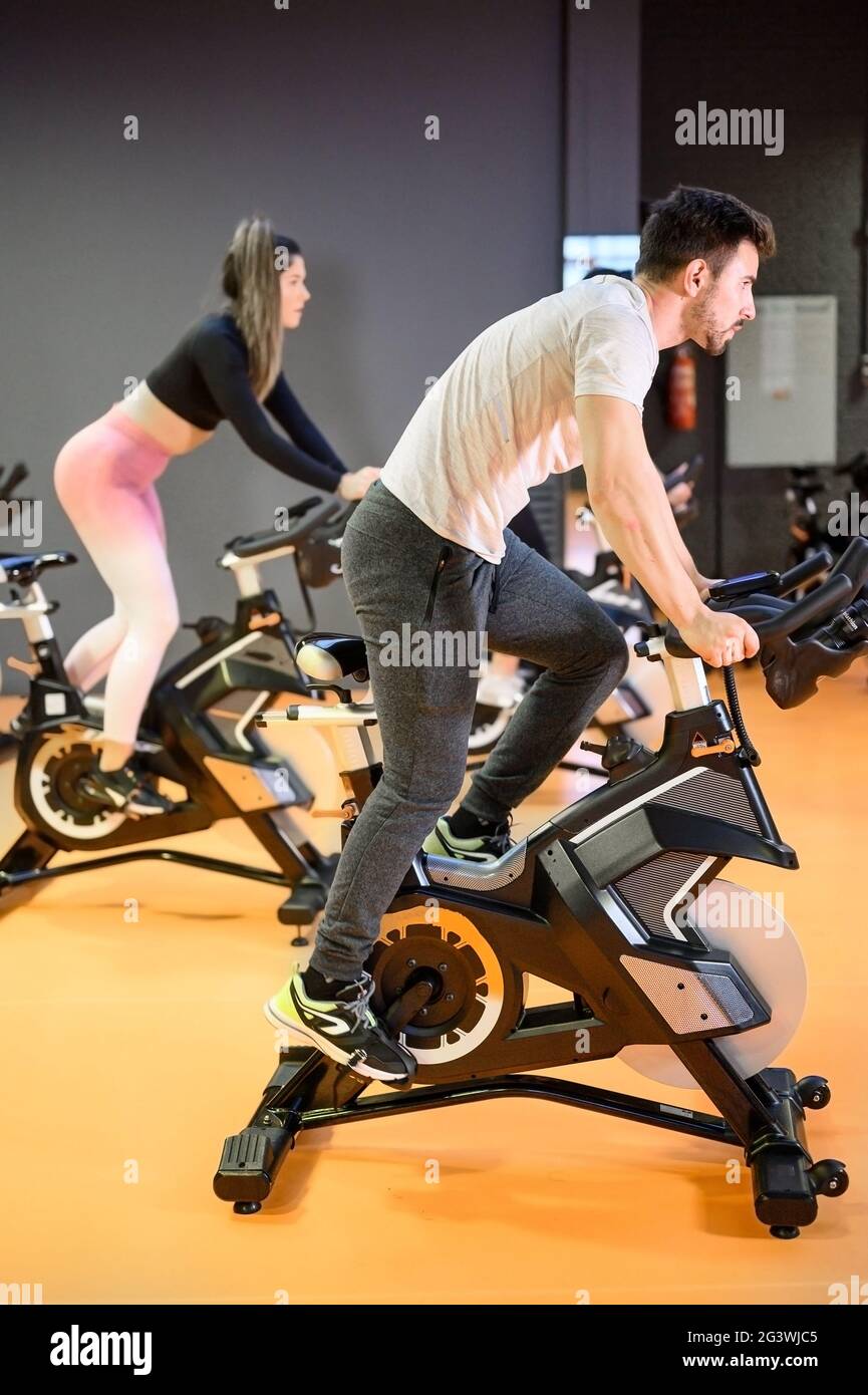 Uomo in bicicletta su una moderna bicicletta fitness durante la lezione di spinning di gruppo presso la palestra Foto Stock