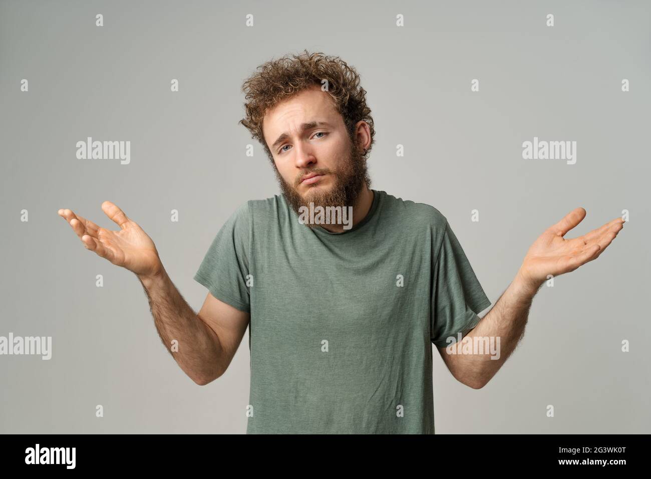 Bell'uomo con capelli ricci che mostra che non conosco il gesto con entrambe le mani isolate su sfondo bianco. Ritratto di ti ha confuso Foto Stock