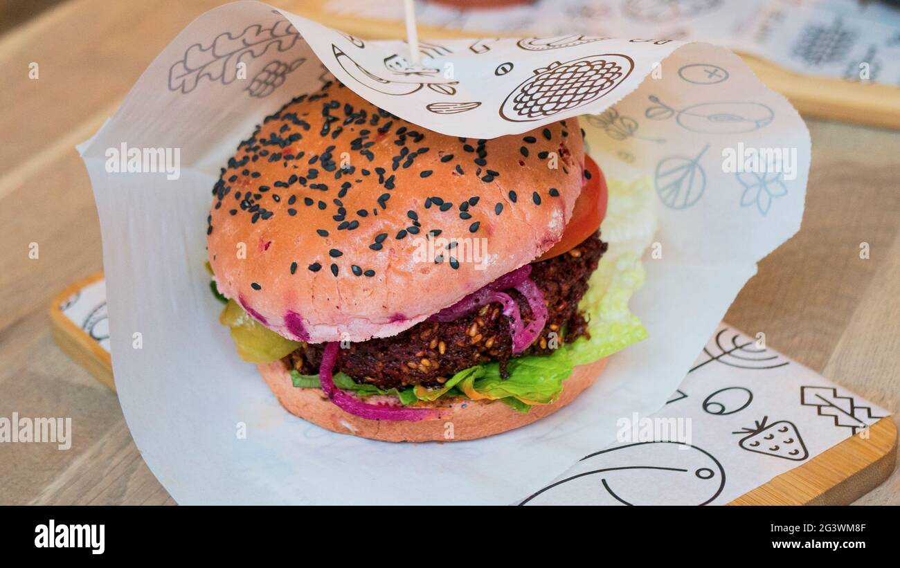 Foto ravvicinata di un hamburger vegetariano con una patina di barbabietole in un panino di sesamo Foto Stock