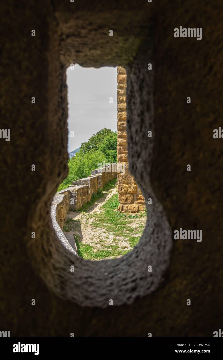 Immagine simbolica: Vista attraverso un buco della serratura nelle mura del castello su parti del complesso esterno del castello. Foto Stock