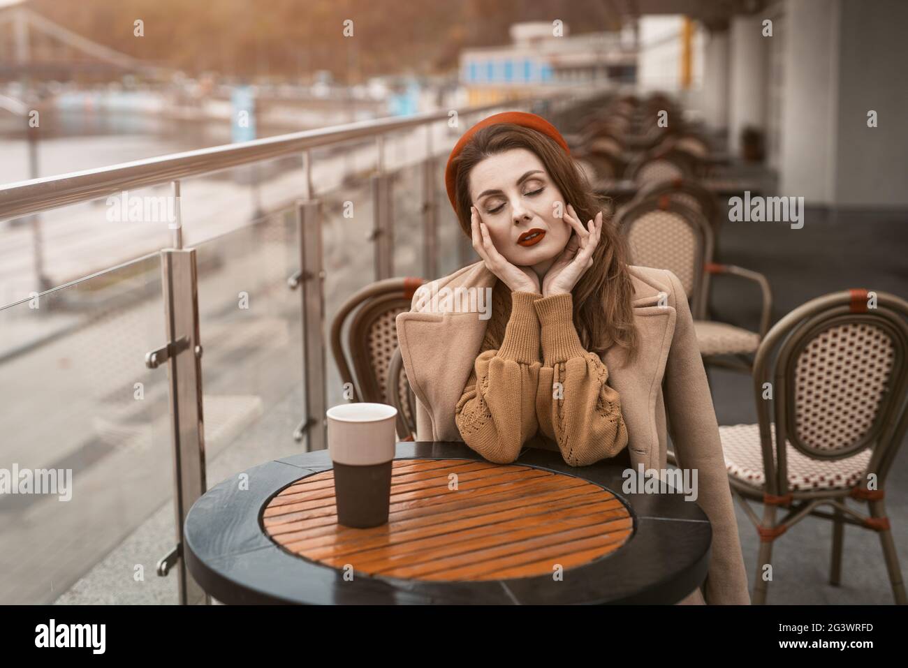 Donna parigina con tazza da caffè in città in serata. Donna affascinante che si gode la sua tazza di caffè seduto in una primavera all'aperto Foto Stock