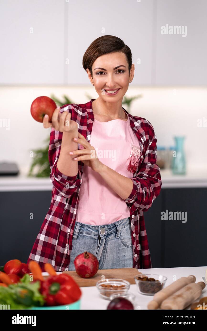 Apple in mano donna felice selezionare frutta cucina a nuova cucina guardando fotocamera. Casalinga cucina torta di mele in piedi al ki Foto Stock