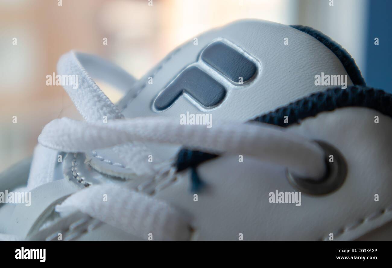Sneaker atletiche bianche con lacci. I lacci bianchi sono legati da vicino. Sfondo sfocato. Concetto sportivo. Famoso logo di marca fila. Elegante e alla moda Foto Stock