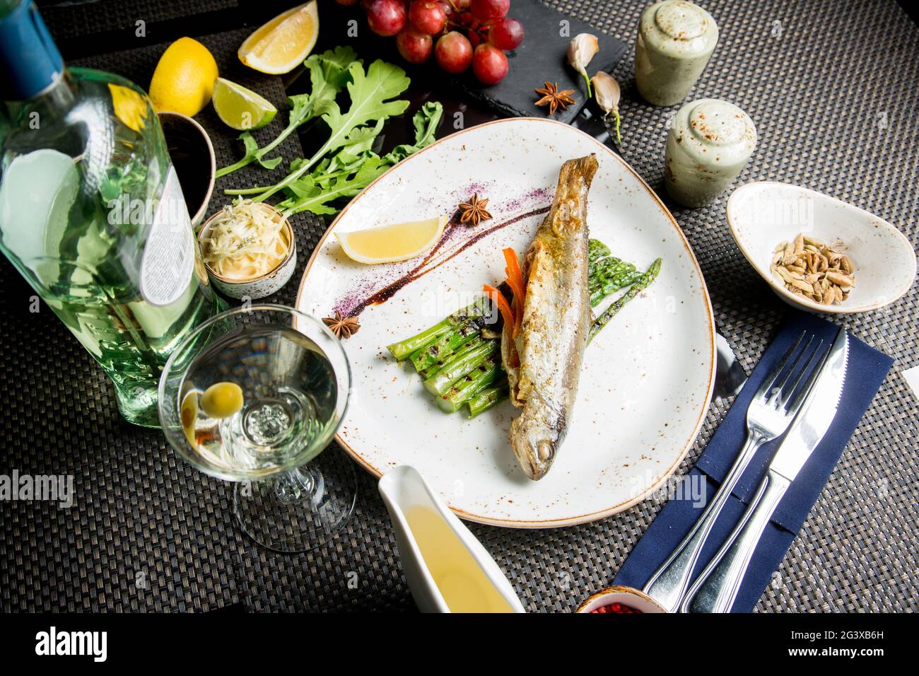 Carcassa intera di trota di mare sulla griglia. Pesce rosso fritto con verdure e salsa. Primo piano. Concetto - cibo, prelibatezze. Foto Stock