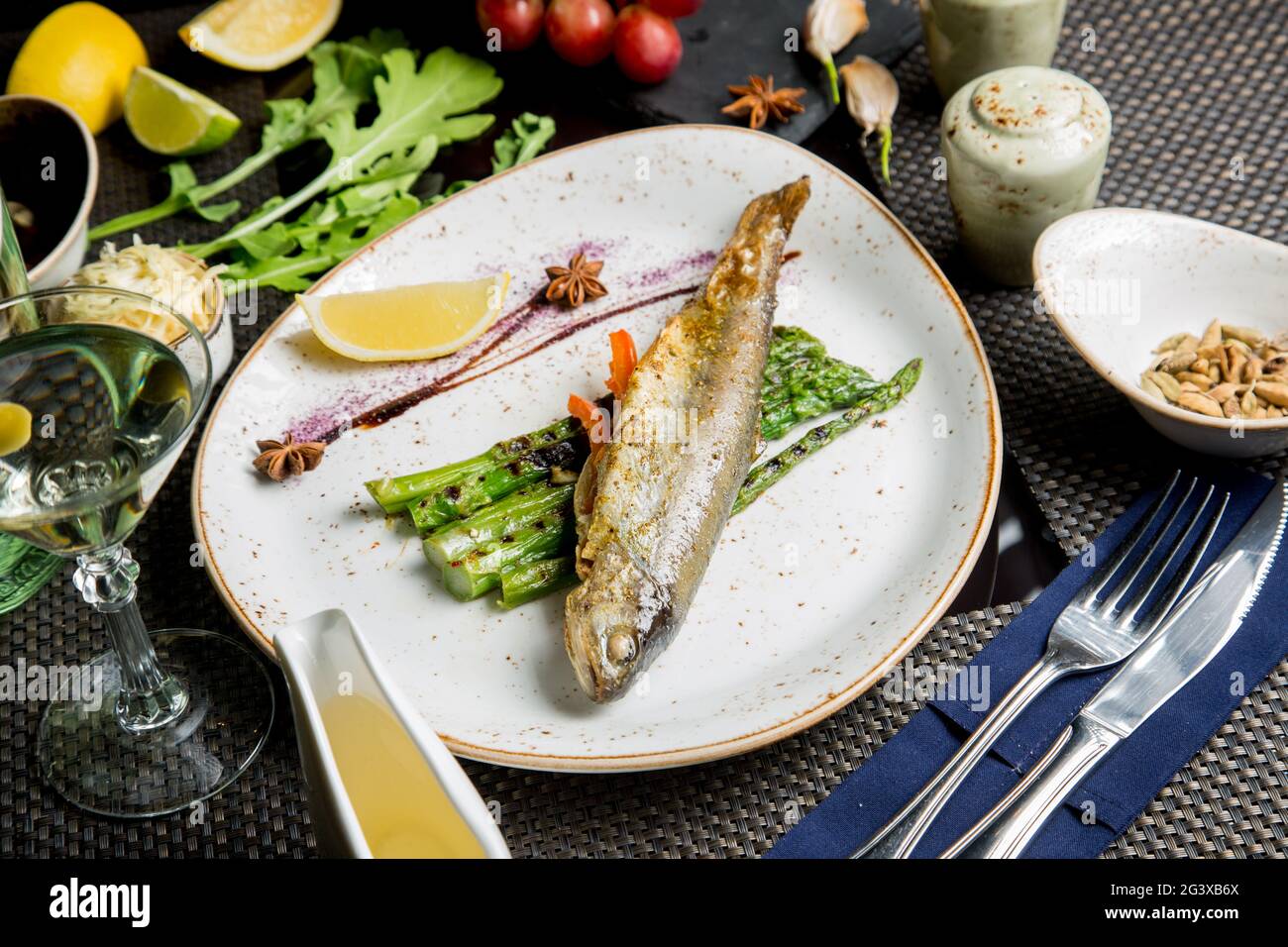 Carcassa intera di trota di mare sulla griglia. Pesce rosso fritto con verdure e salsa. Primo piano. Concetto - cibo, prelibatezze. Foto Stock