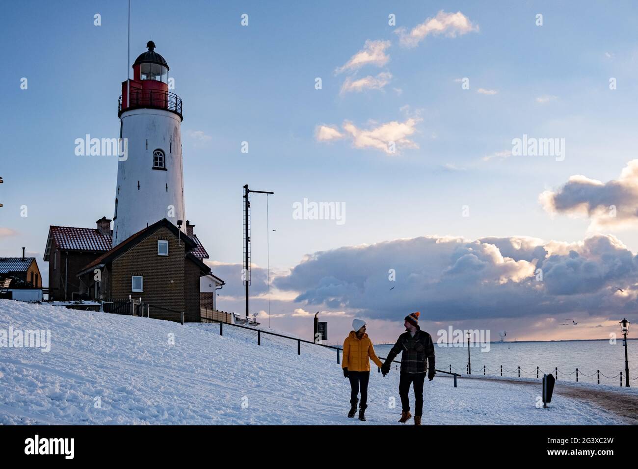 Coppia di uomini e donne al faro di Urk Paesi Bassi durante l'inverno nella neve Foto Stock