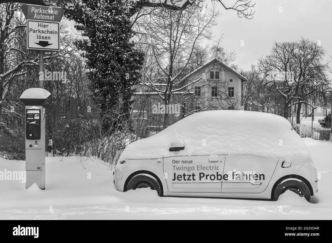 Inverno in città â auto elettrica nel parcheggio e coperto di neve. Foto Stock
