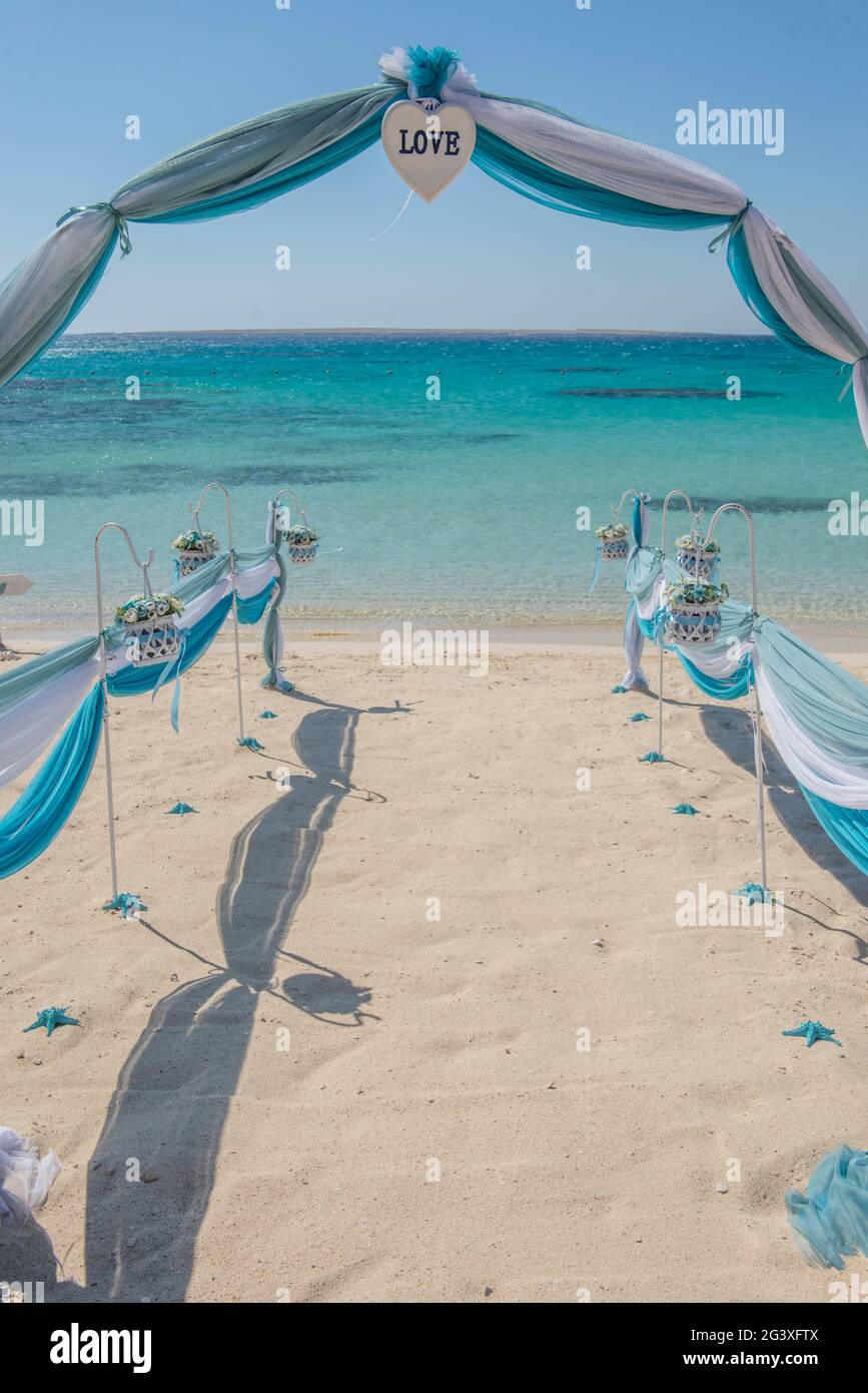 Il setup di giorno di nozze matrimonio corsia con tendaggi e arco sulla sabbiosa spiaggia tropicale paradiso per aprire Sfondo oceano Foto Stock