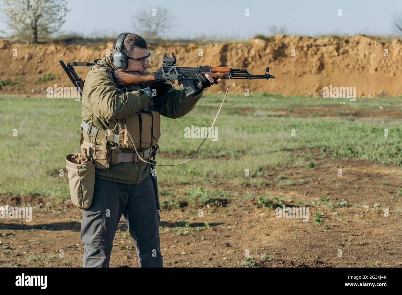 L'uomo bianco in uniforme militare spara un AK a un raggio di tiro Foto Stock