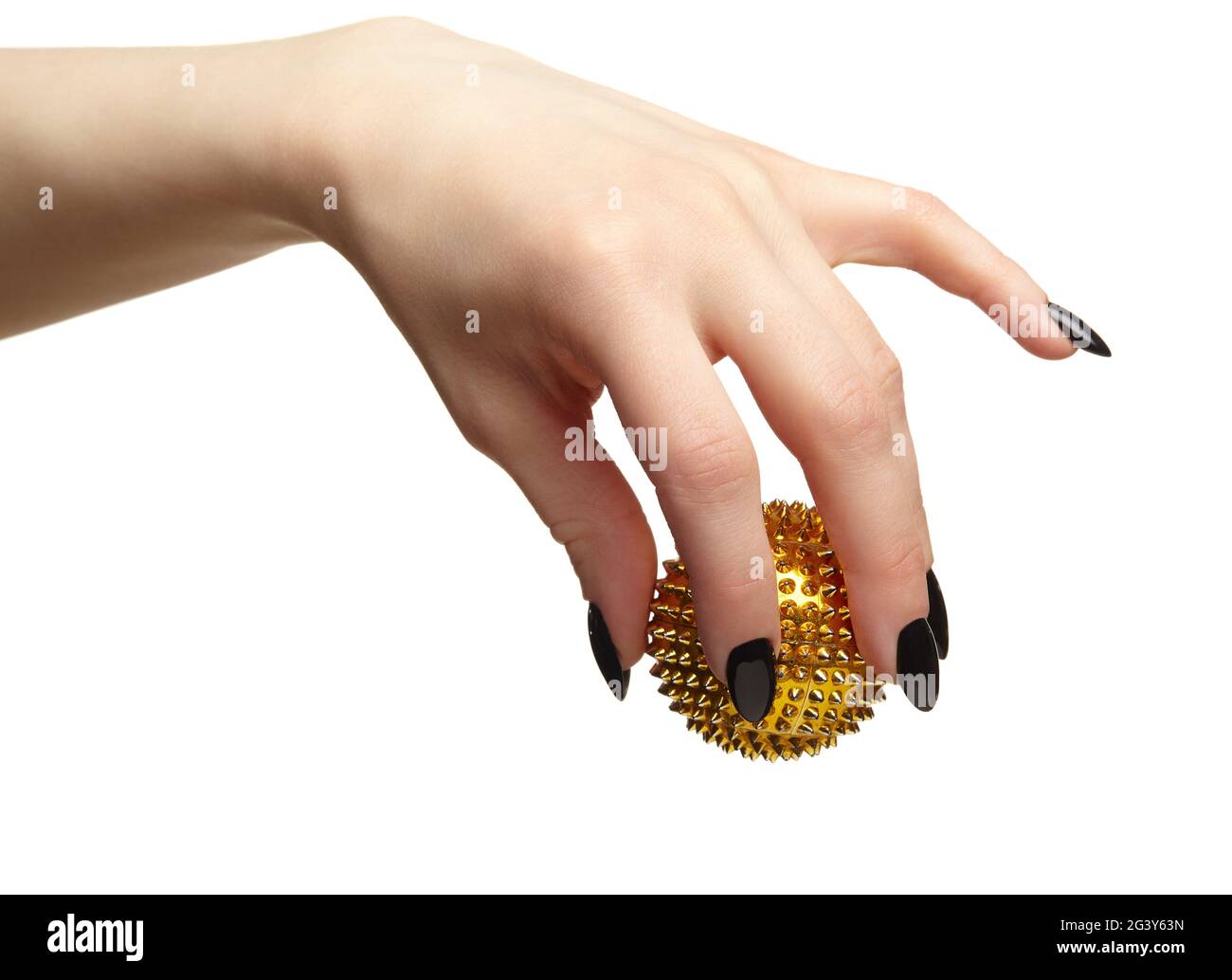 Mano femminile con unghie nere manicure e palla di massaggio dorata con punte nelle dita. Foto Stock