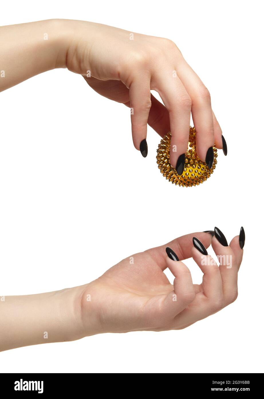 Mano femminile con unghie nere manicure e palla di massaggio dorata con punte nelle dita. Foto Stock