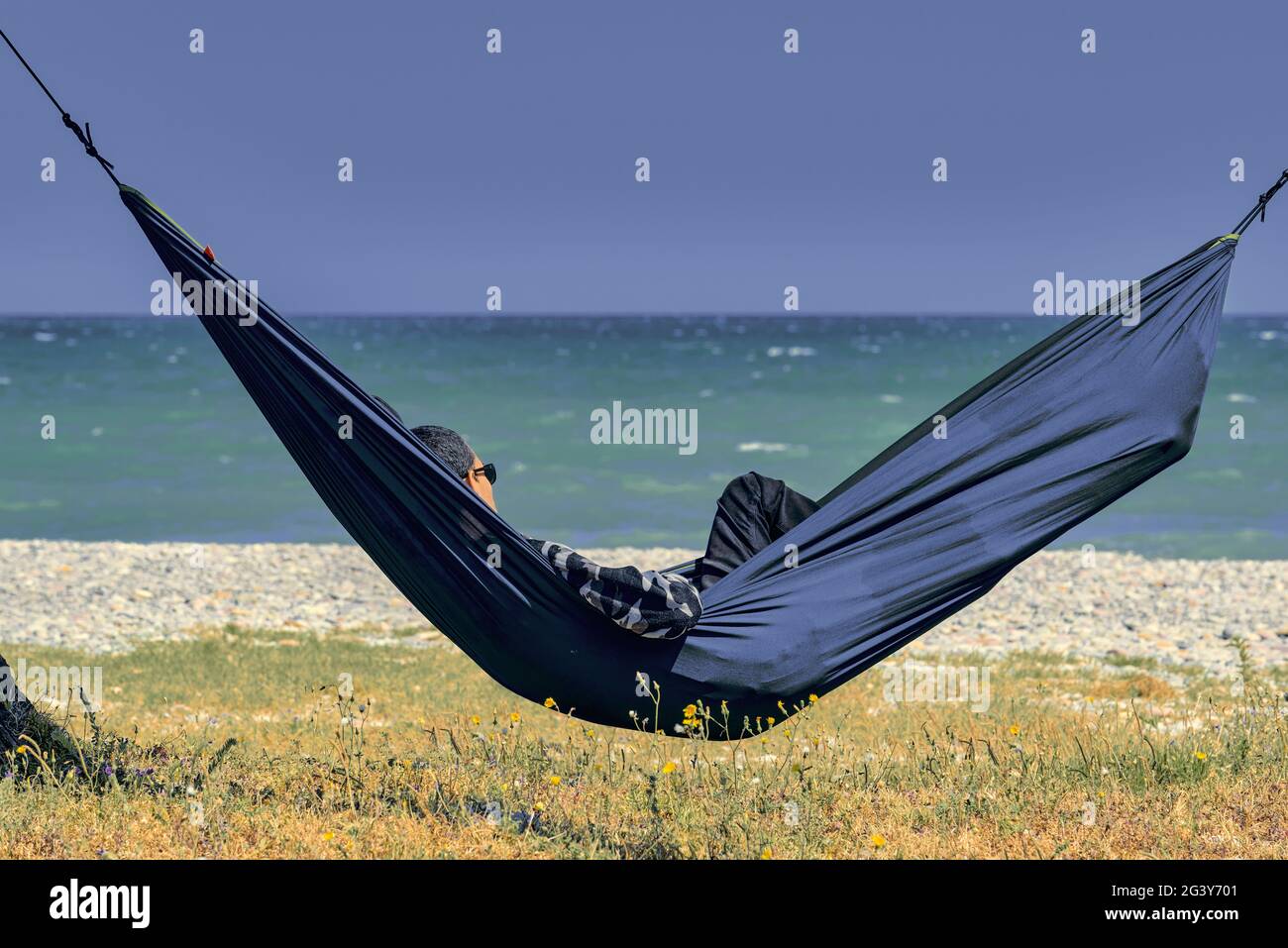 Uomo sdraiato su un'amaca blu con occhiali sulla spiaggia di Moncofa,  provincia di Castellon, Spagna, Europa Foto stock - Alamy