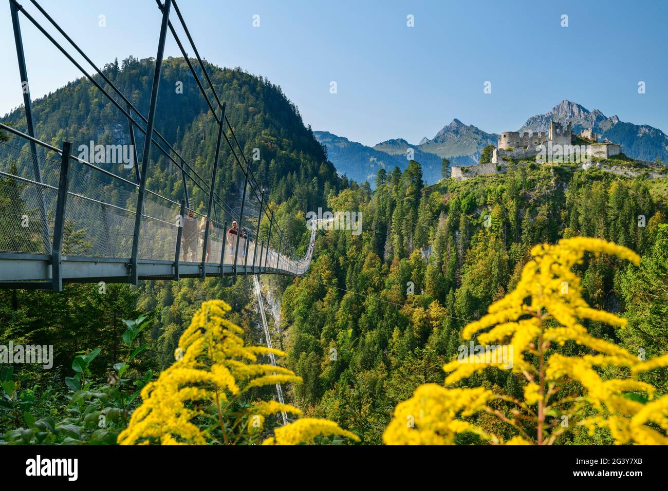 Molte persone camminano sul ponte di corda Highline 179 con le rovine del castello di Ehrenberg sullo sfondo, Reutte, Tirolo, Austria Foto Stock