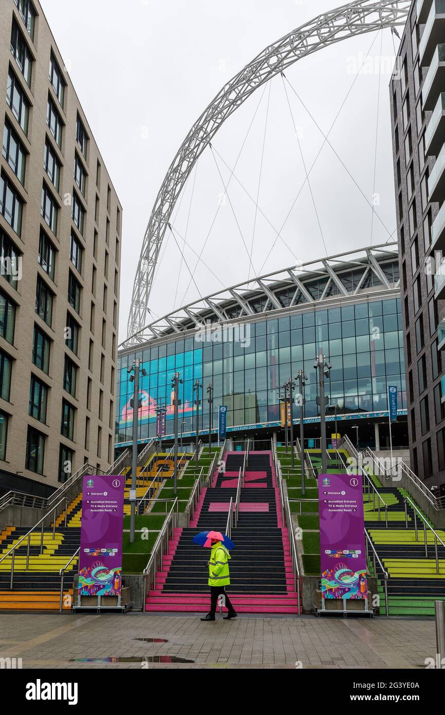 Wembley Stadium, Wembley Park, Regno Unito. 18 Giugno 2021. La steward si ripara sotto un ombrello di fronte alla scalinata di Wembley Stadium, mentre la pioggia torrenziale cade in tutta Londra. La Scozia affronterà l'Inghilterra nella seconda partita del Gruppo D del Campionato europeo di calcio UEFA allo stadio di Wembley questa sera con un calcio d'inizio alle 20:00. Credit: amanda Rose/Alamy Live News Foto Stock