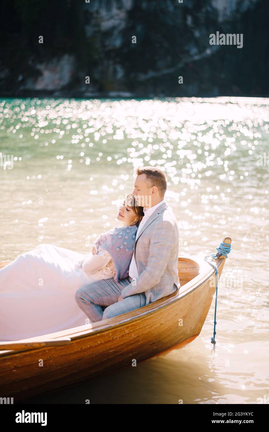 Una coppia di nozze è seduta in una barca di legno sul Lago di Braies in Italia. Sposi novelli in Europa, sul lago di Braies, nelle Dolomiti Foto Stock