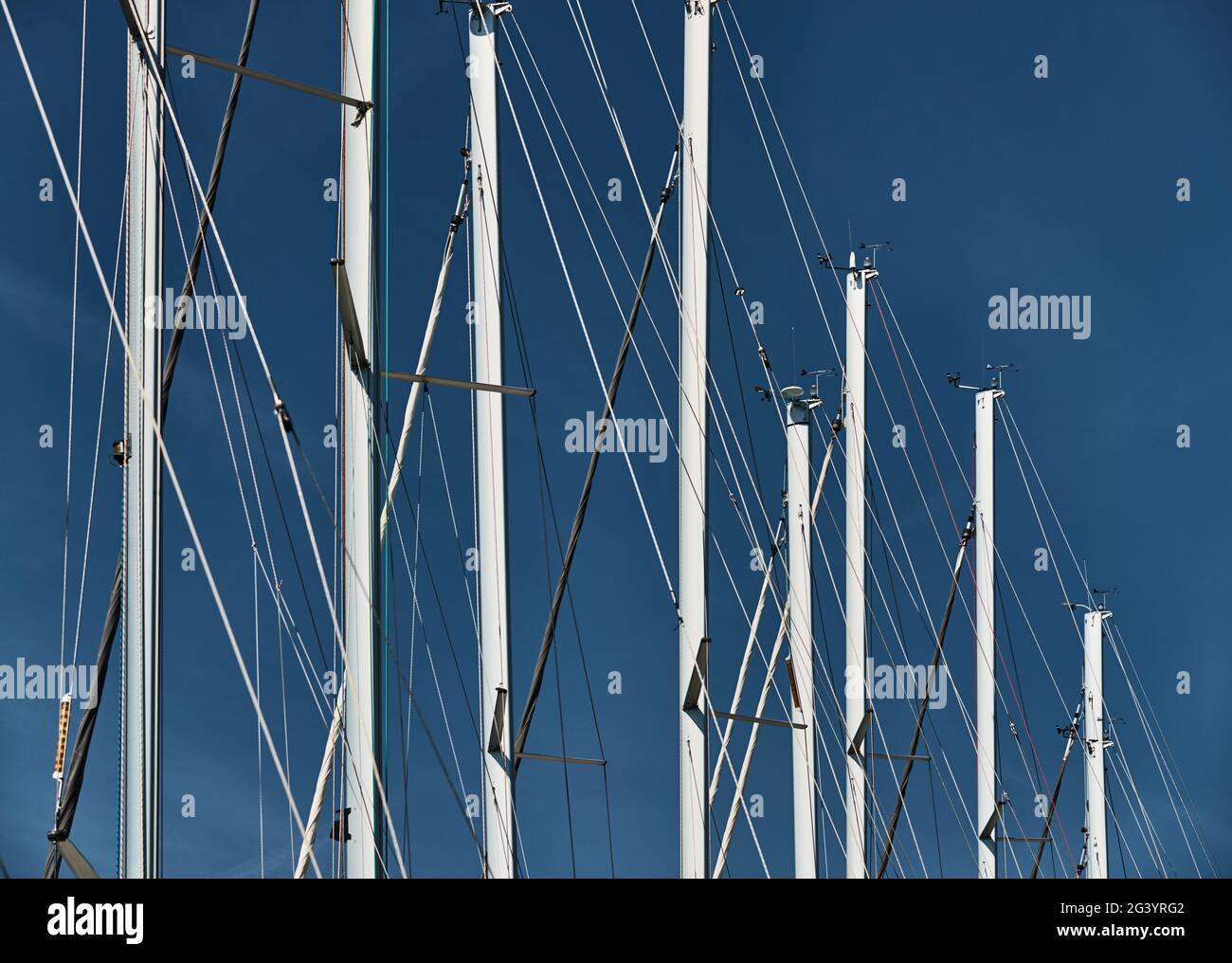Il numero di alberi di barche a vela con il cielo blu sullo sfondo, una regata velica, riflesso di alberi su acqua, corde e allume Foto Stock Il numero di alberi di barche a vela con il cielo blu sullo sfondo, una regata velica, riflesso di alberi su acqua, corde e allume Foto Stock