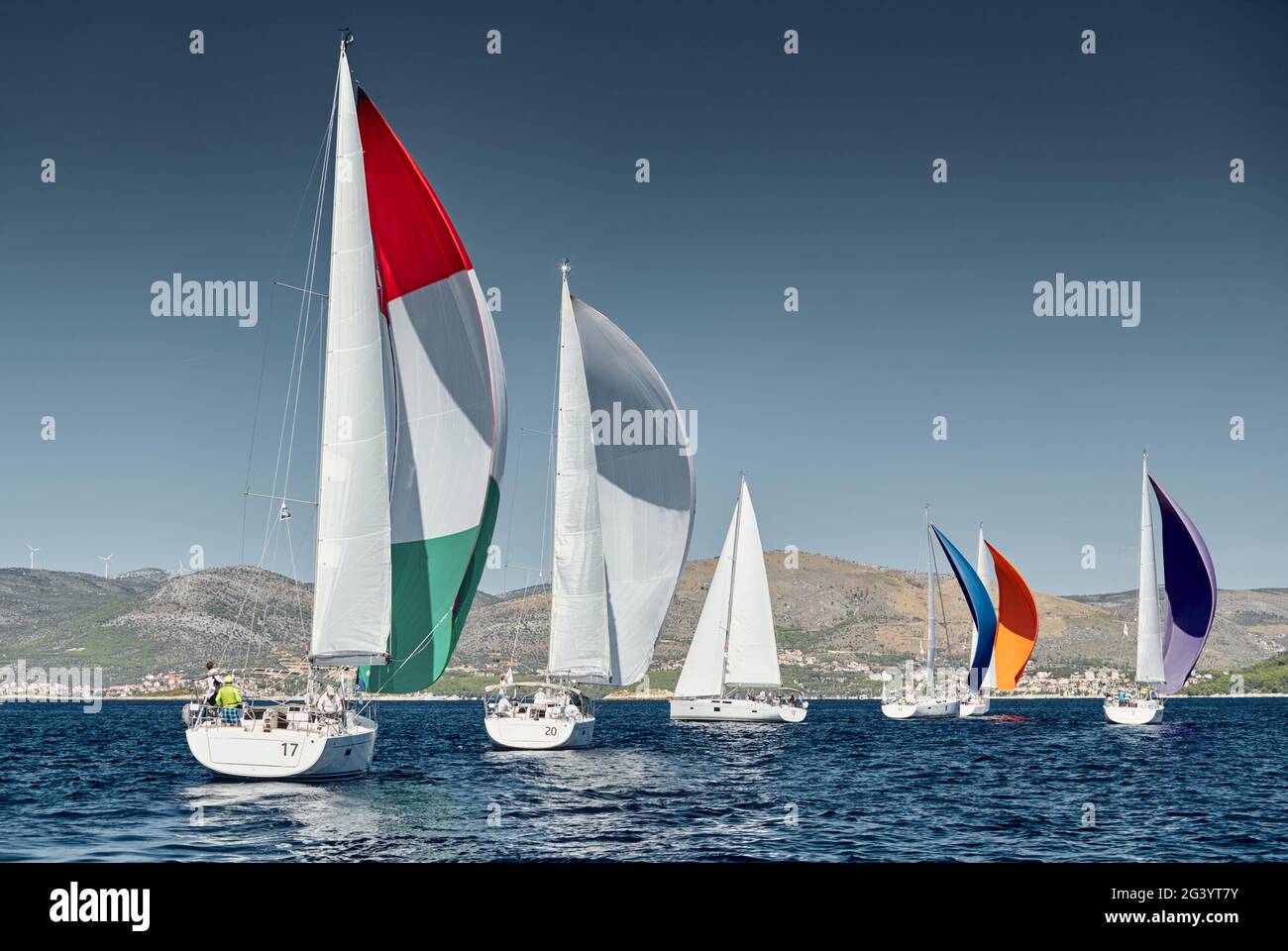 Le barche a vela gareggiano in una regata velica al tramonto, gara di barche a vela, riflesso di vele sull'acqua, spinnaker multicolore, numero Foto Stock Le barche a vela gareggiano in una regata velica al tramonto, gara di barche a vela, riflesso di vele sull'acqua, spinnaker multicolore, numero Foto Stock