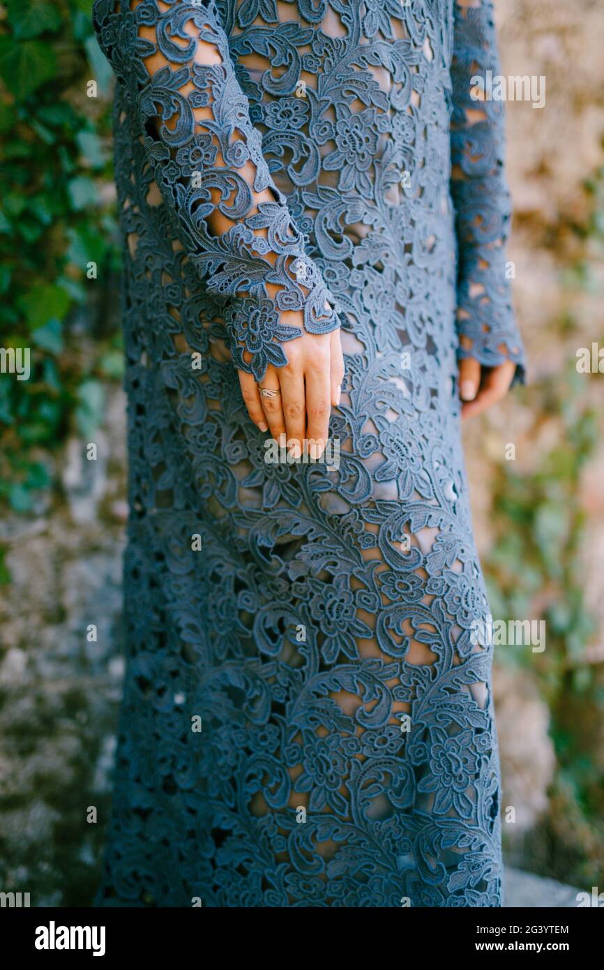 Mani della donna in elegante abito in pizzo blu in piedi e pareti intrecciate con edera, primo piano Foto Stock