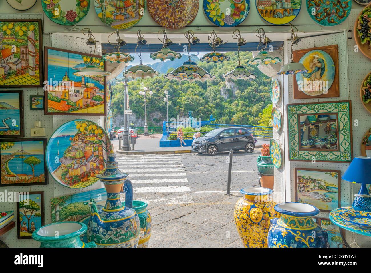 Vietri-Italy - 02.23.2019: Bella vista dall'interno di una bottega di ceramiche. All'aperto un parco verde e un parcheggio auto. Molte tavole artistiche artigianali Foto Stock