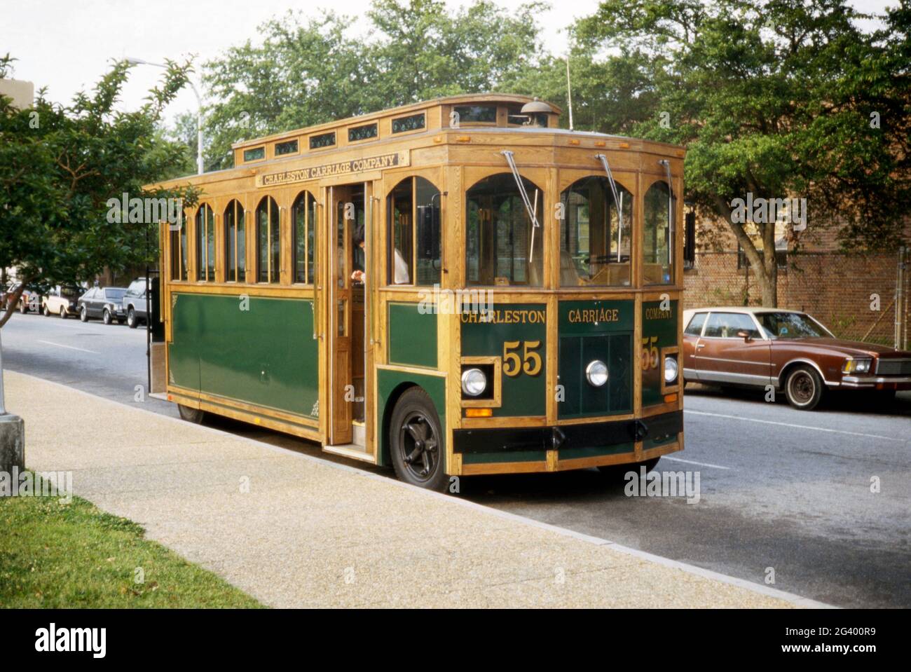 Un ‘trolley’ turistico – essenzialmente un autobus motorizzato fatto assomigliare a un trolley, un tram o un tram – che offre tour storici delle parti coloniali storiche di Charleston, Carolina del Sud, USA nel 1984. Con abbondanza di legno verniciato in esposizione, il numero 55 è stato gestito dalla Charleston Carriage Company. Charleston è la città più grande dello stato americano del South Carolina. Questa immagine è tratta da un vecchio lucido a colori americano amatoriale Kodak – una fotografia d'epoca degli anni '80. Foto Stock