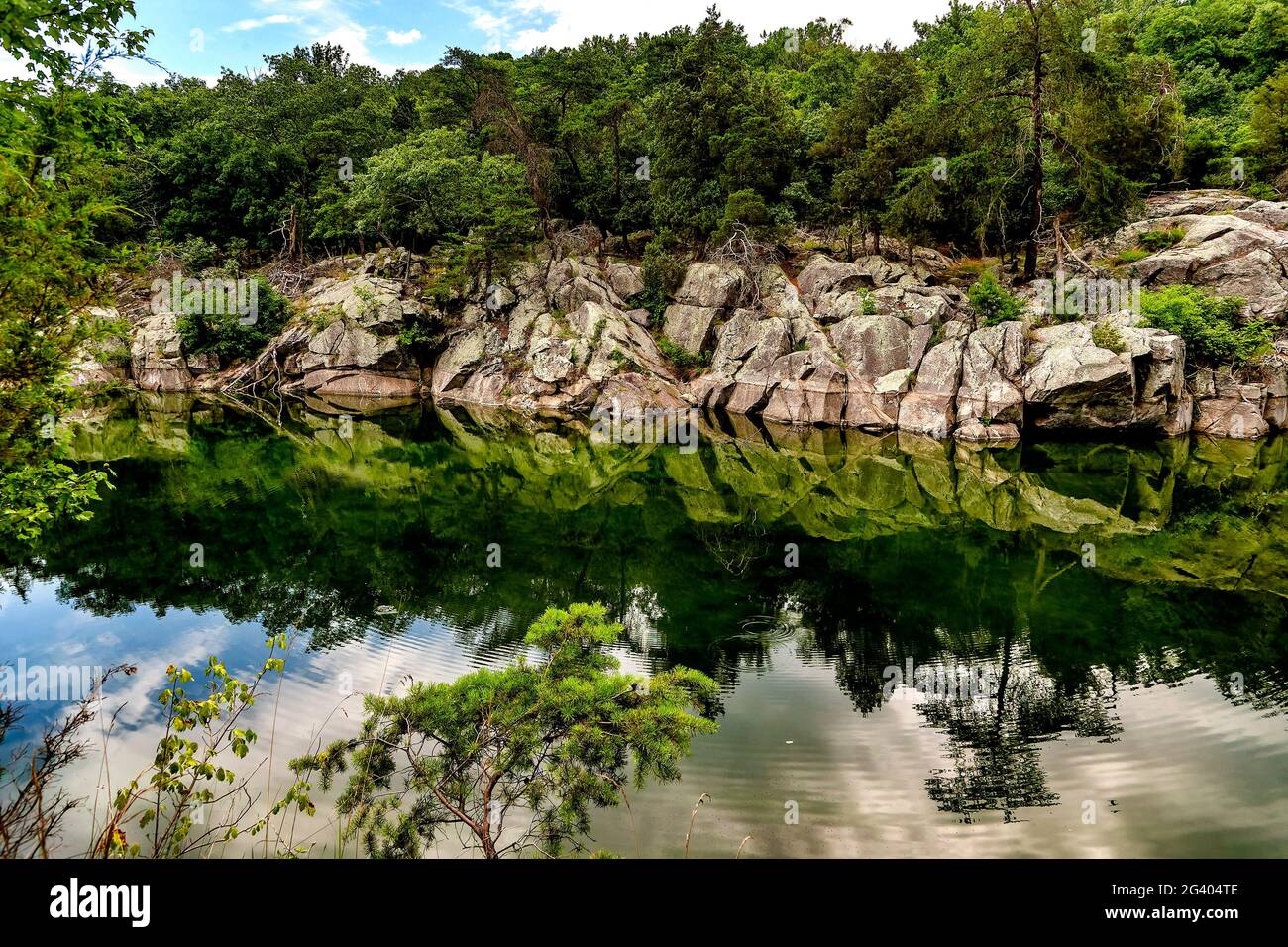Parete bianca bianca di roccia sbiancata riflessa nelle calme acque del lago Foto Stock
