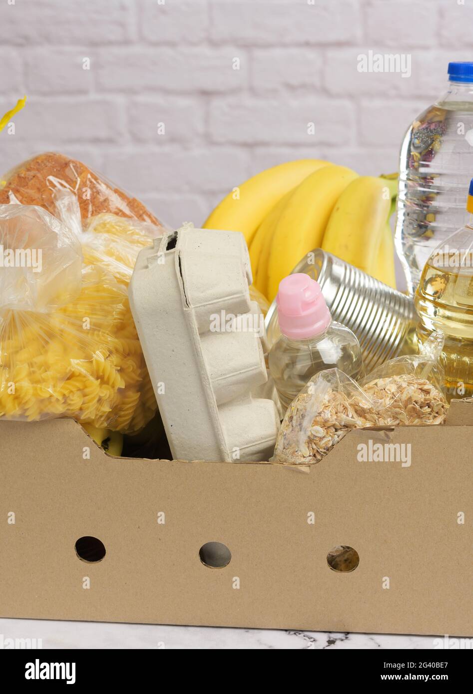 Scatola di cartone con vari prodotti, frutta, pasta, olio di girasole in bottiglia di plastica e conservazione Foto Stock