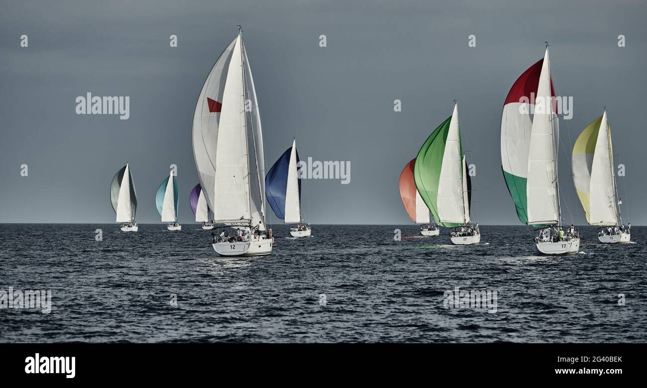 Le barche a vela gareggiano in una regata velica al tramonto, gara di barche a vela, riflesso di vele sull'acqua, spinnaker multicolore, numero Foto Stock Le barche a vela gareggiano in una regata velica al tramonto, gara di barche a vela, riflesso di vele sull'acqua, spinnaker multicolore, numero Foto Stock