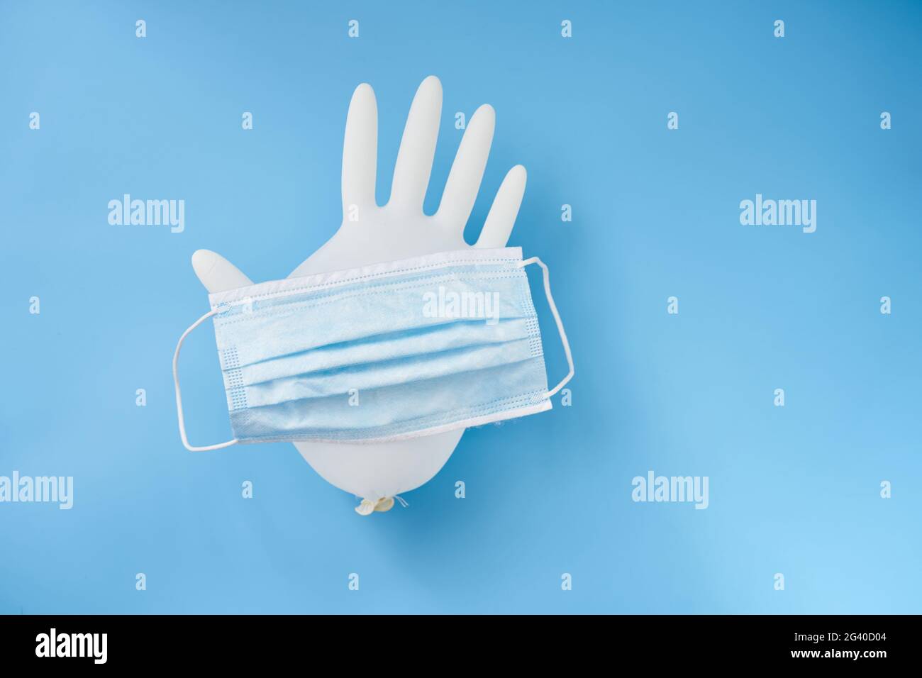 Primo piano di un guanto isolato e di una maschera facciale su sfondo blu. Protezione personale durante la pandemia mondiale Foto Stock