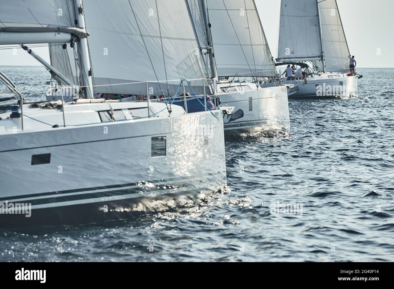 Inizio della regata velica, le barche a vela gareggiano in una regata velica al tramonto, riflesso del sole a bordo della barca, tempo limpido Foto Stock Inizio della regata velica, le barche a vela gareggiano in una regata velica al tramonto, riflesso del sole a bordo della barca, tempo limpido Foto Stock
