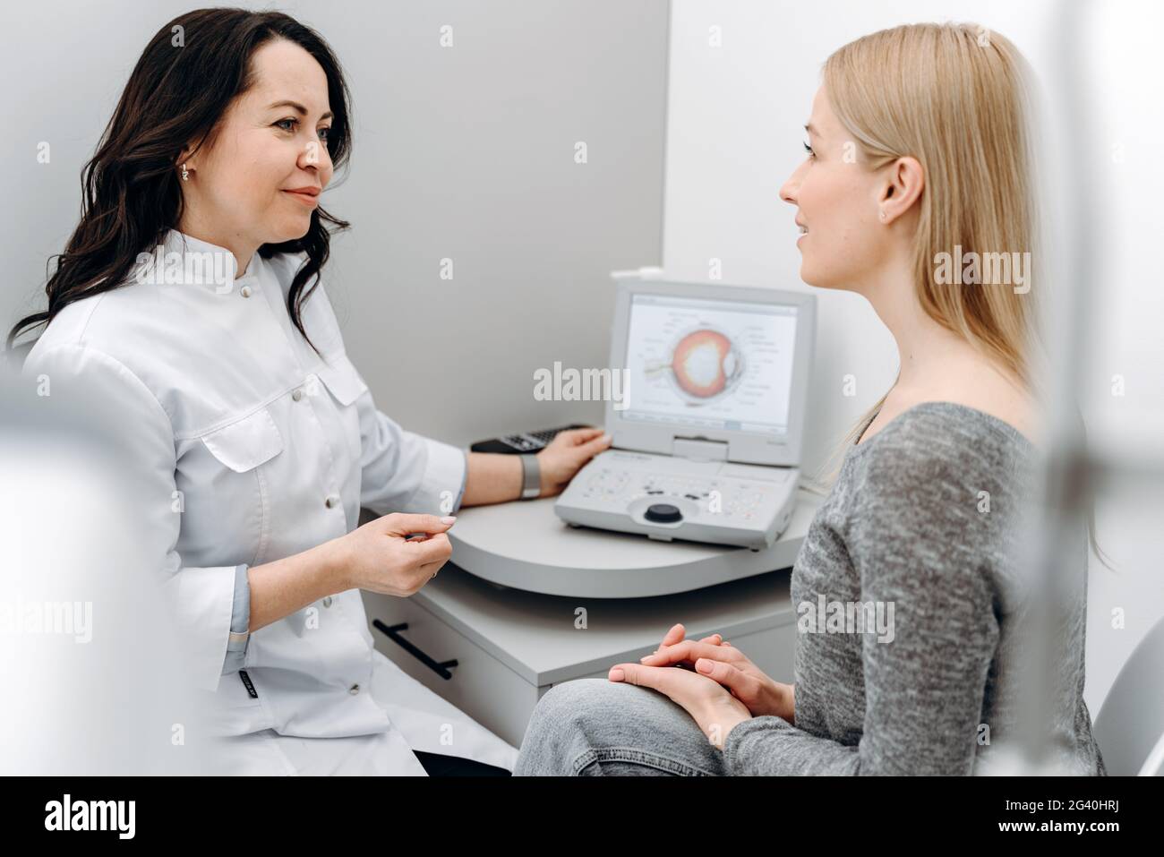 Un medico sensibile e piacevole dice al paziente la condizione degli occhi. Il concetto di mantenere la propria salute. Foto Stock