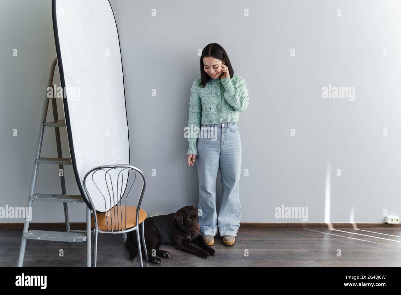 Bruna sorridente lavora in studio, su uno sfondo di una parete grigia, un bel cane non è seduto in un cerchio. Concetto - il cane è un amico fedele o Foto Stock